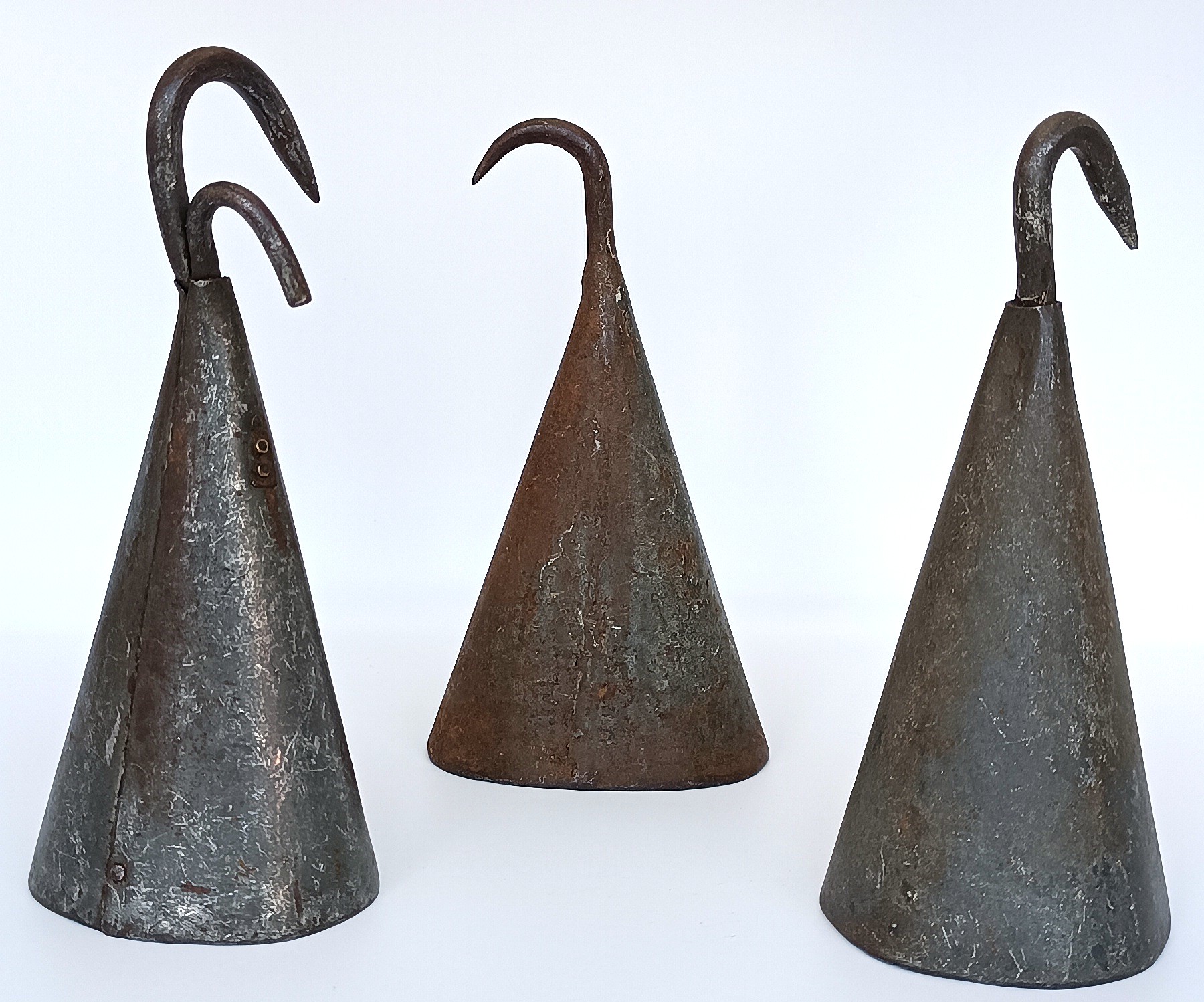 Three antique forged iron butcher pig scraper bells with curved hooks and aged patina