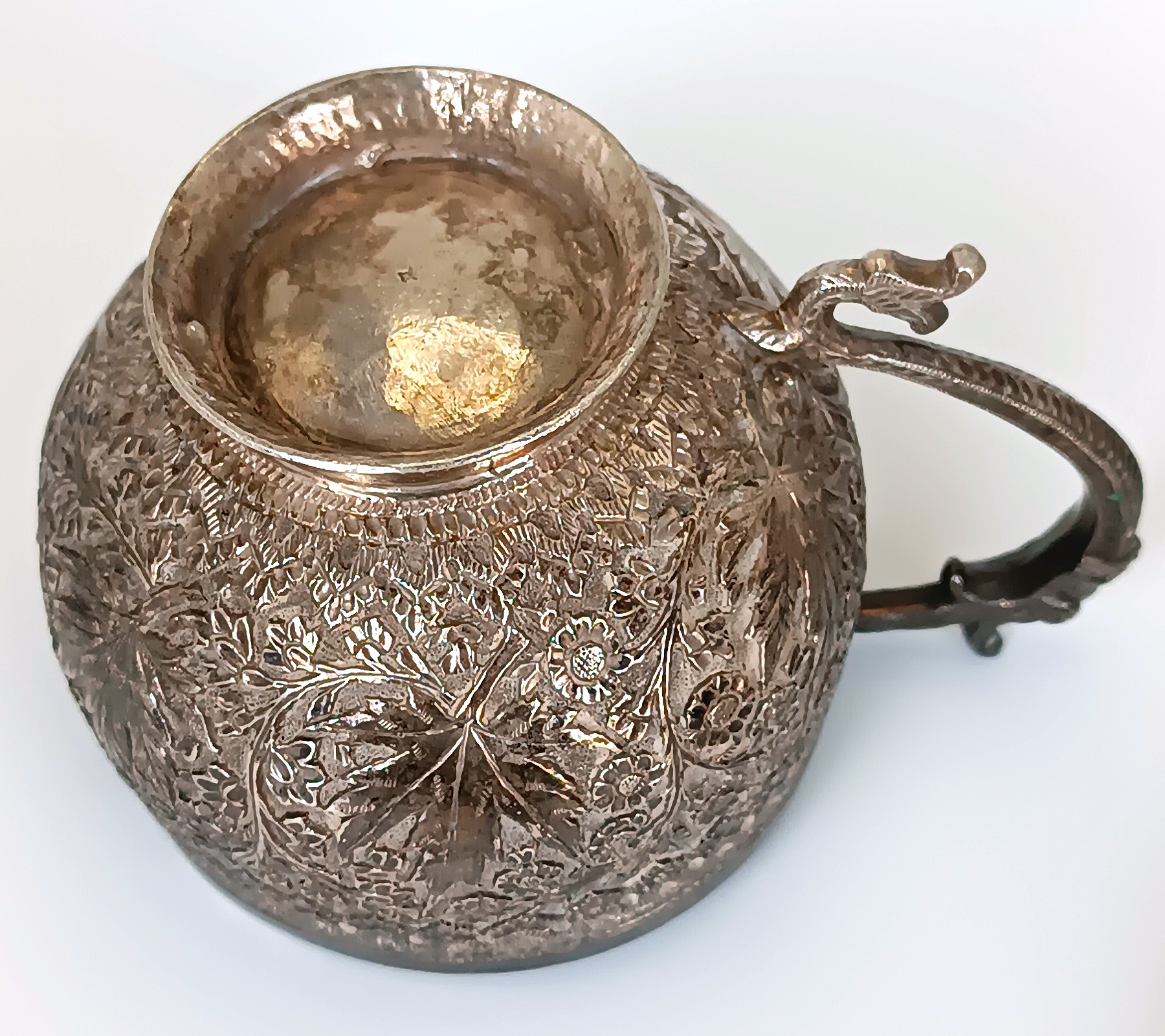 Underside of antique Kashmiri Anglo-Indian cup with floral chased decoration, raised foot and zoomorphic handle, circa 1900
