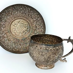 Antique Kashmiri Anglo-Indian cup and saucer with silver-plated floral decoration and zoomorphic handle, circa 1900