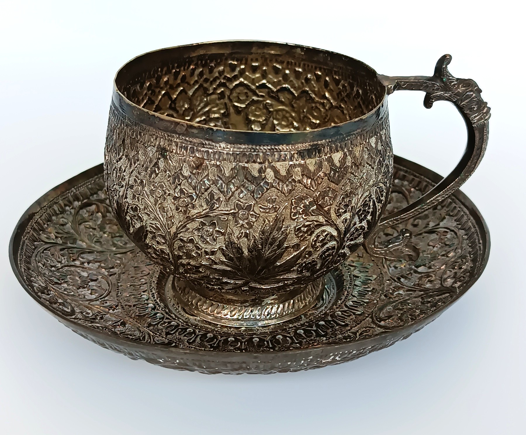 Antique Kashmiri Anglo-Indian cup and saucer with floral chased decoration and zoomorphic handle, circa 1900