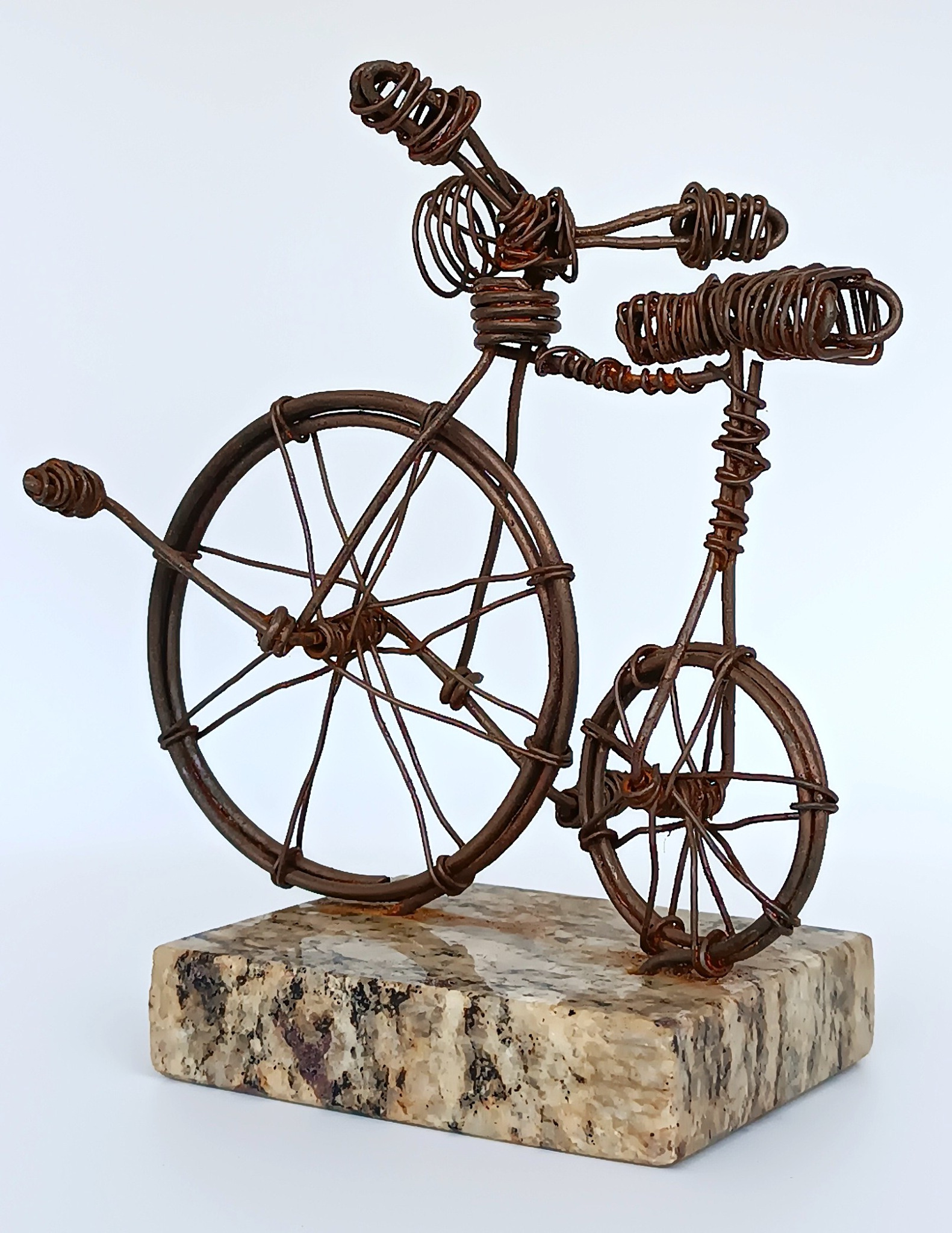 Front three-quarter view of handmade Penny-farthing wire bicycle sculpture on stone base