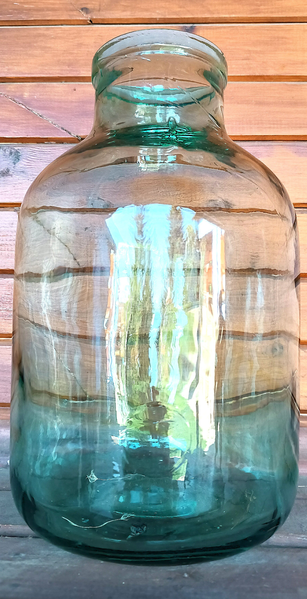 Front view of vintage green glass 8-litre demijohn with wide mouth and thick blue-green glass