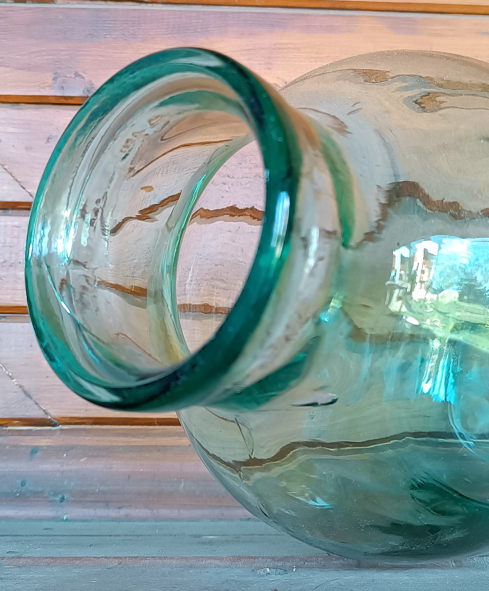 Close-up of the thick rounded neck and rim of a vintage green glass 8-litre demijohn