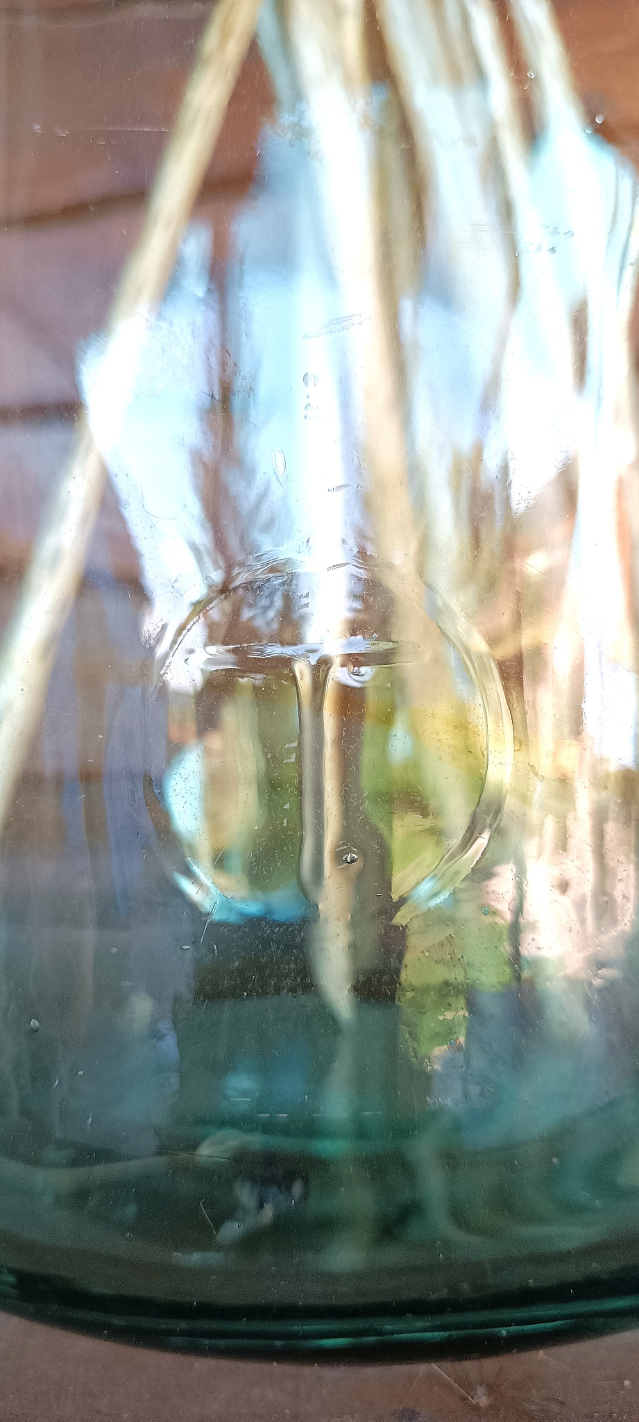 Close-up of embossed T in a circle mark on vintage green glass 8-litre demijohn