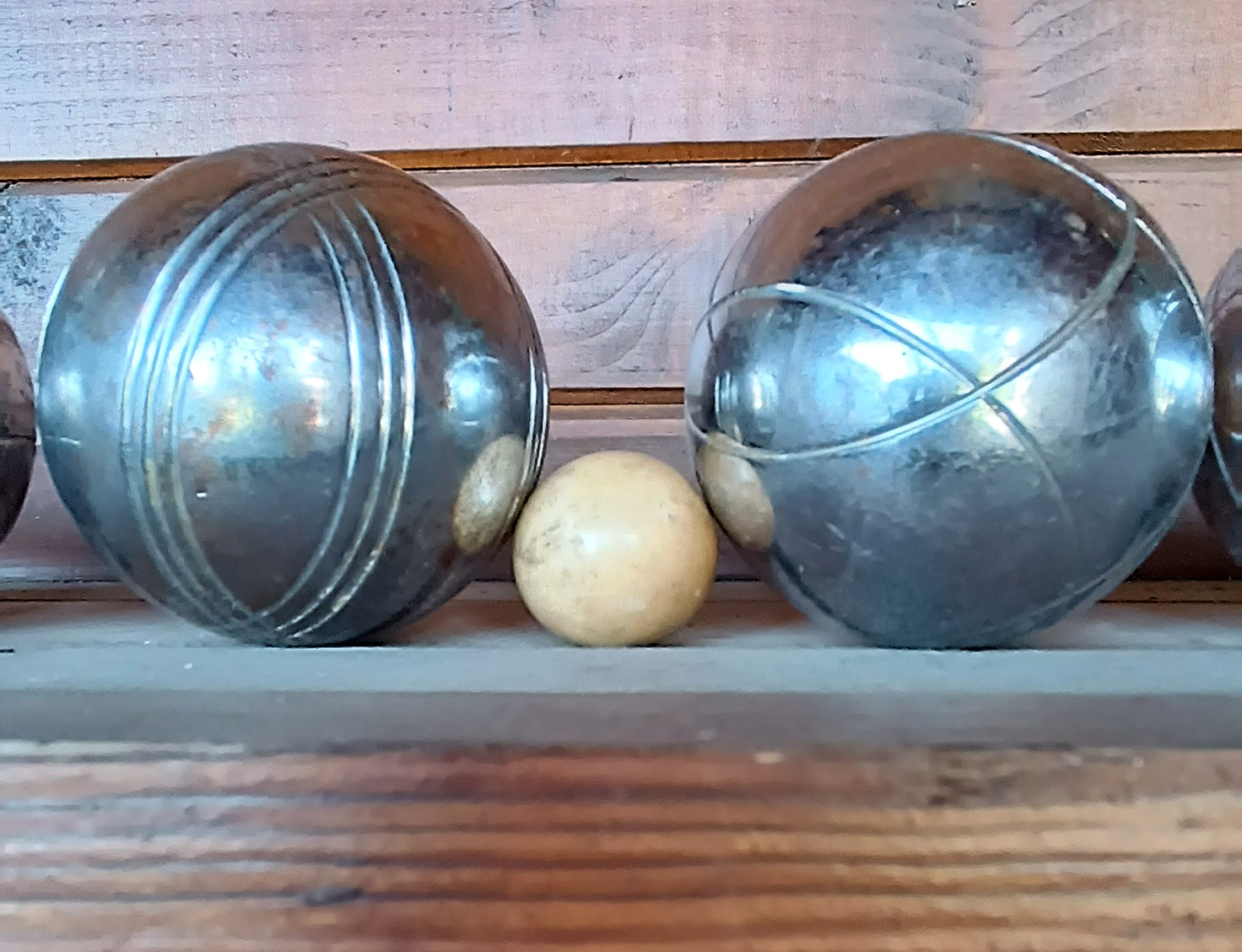 Close-up of vintage pétanque boules with engraved line patterns and a wooden cochonnet