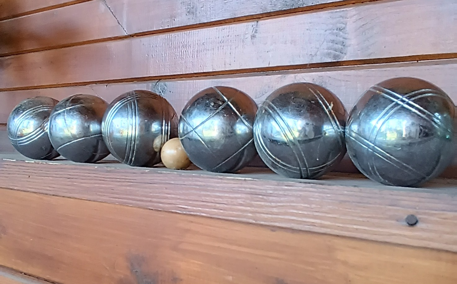 Side view of vintage pétanque set with 6 solid metal boules and a wooden cochonnet