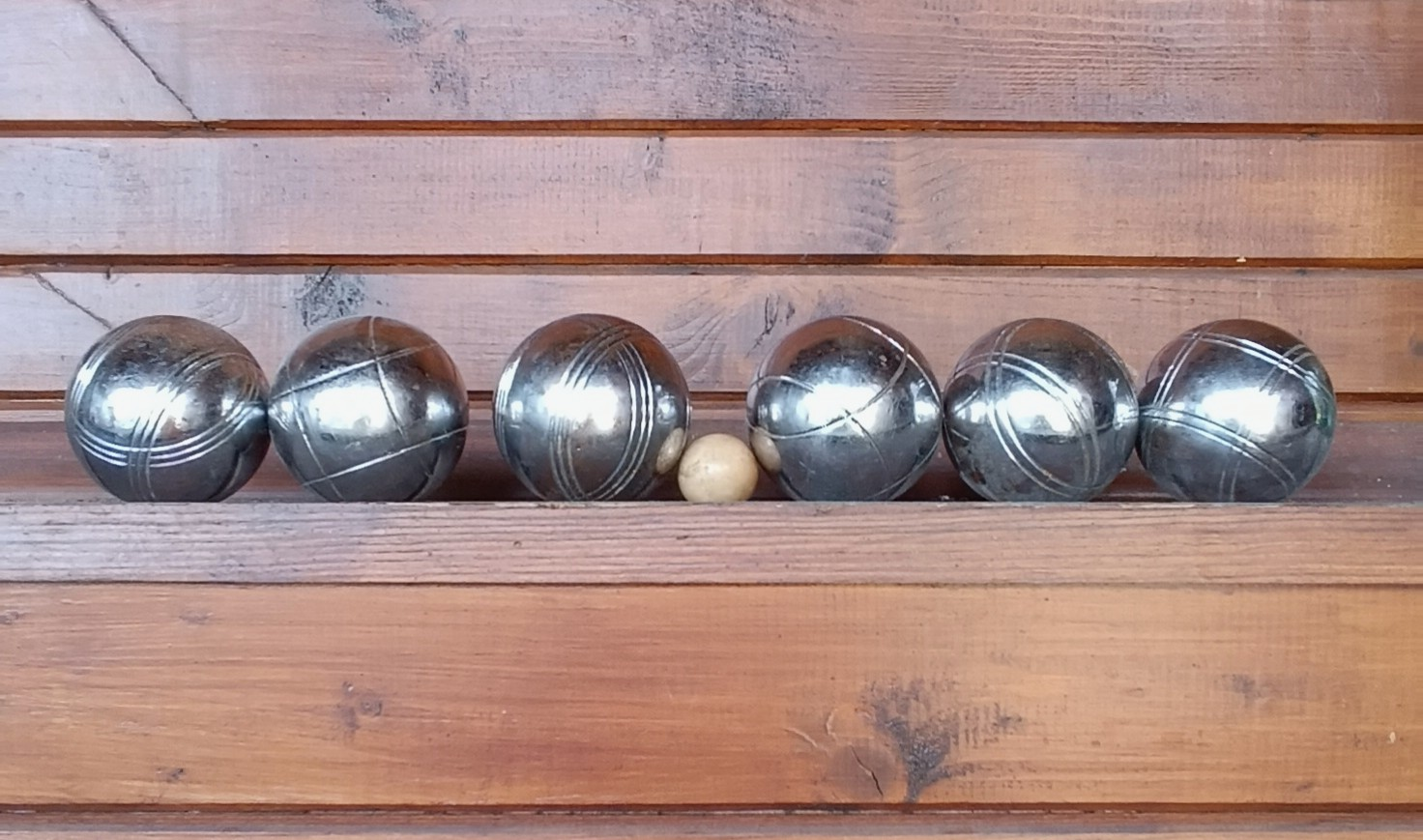 Vintage pétanque set with 6 solid metal boules arranged in three engraved pairs and a wooden cochonnet