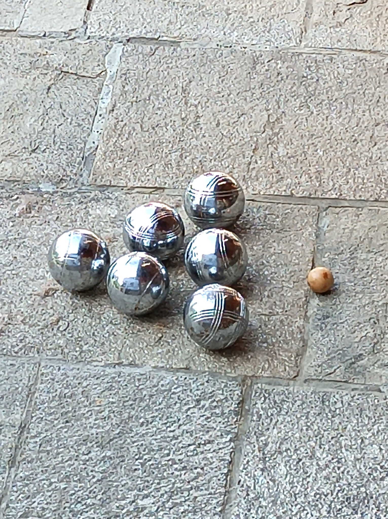 Vintage pétanque set with 6 solid metal boules and a wooden cochonnet arranged for play