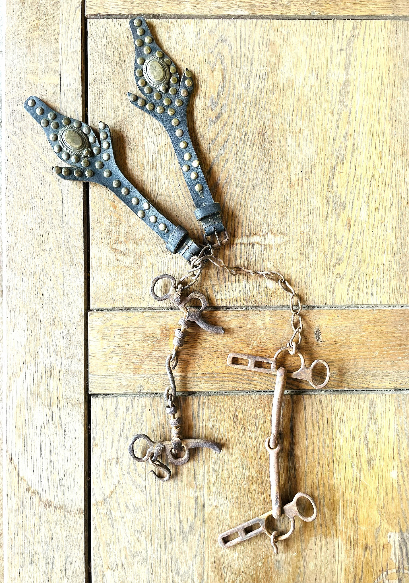 Antique Balkan horse bit with two decorated leather cheekpieces, brass studs, oval plaques, iron chain and metal fittings