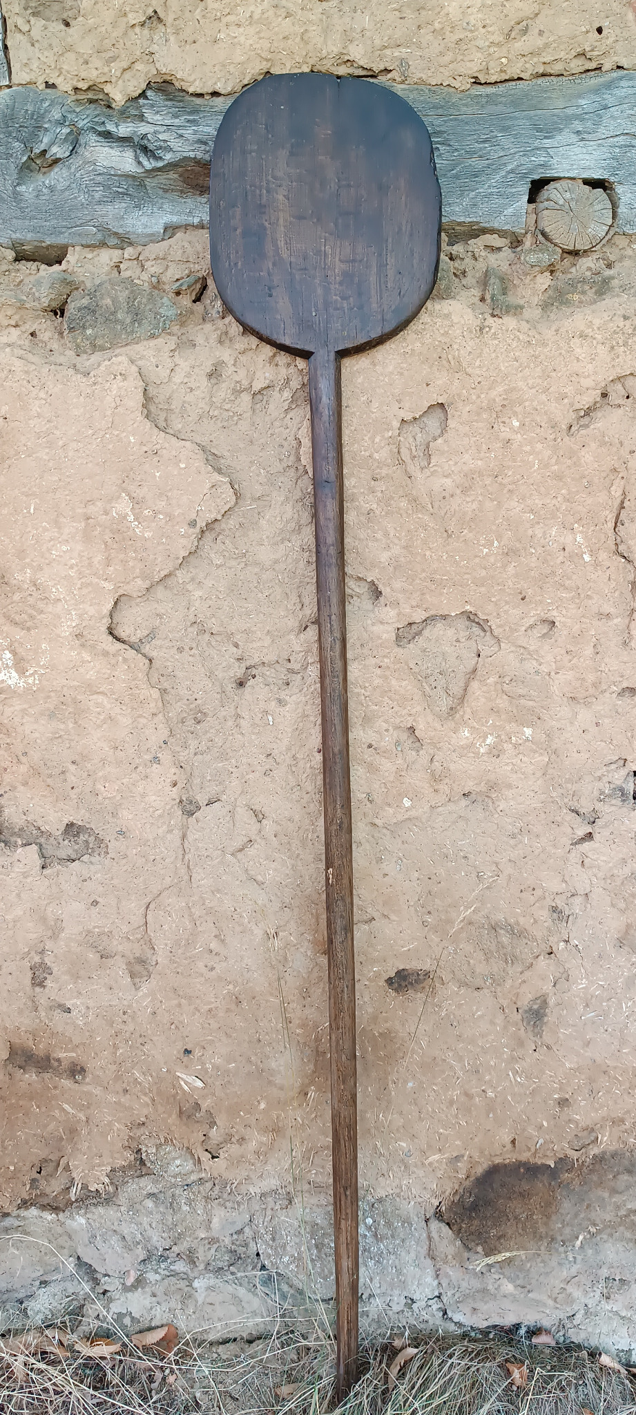 Antique Balkan wooden bread peel with long handle and dark worn paddle, handmade from one piece of wood, approximately 170 cm long