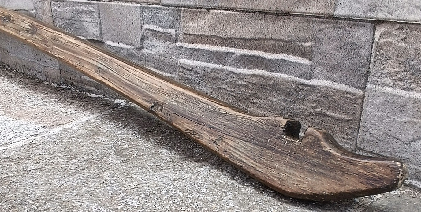 Close-up of an antique Balkan wooden shoulder yoke from the Pavlikeni region showing the carved end slot for hanging water vessels