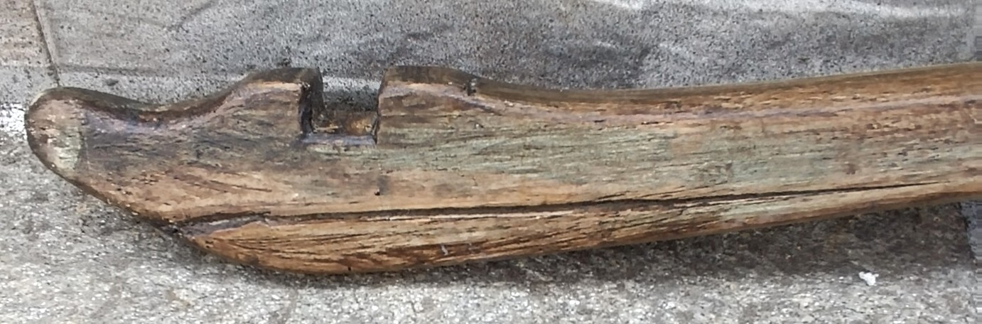 Close-up of an antique Balkan wooden shoulder yoke showing the carved end slot, worn edge and natural patina from long-term use