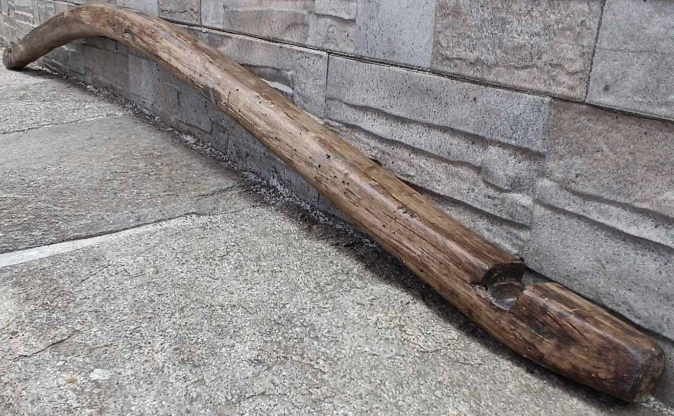 Detailed view of an antique Bulgarian wooden shoulder yoke from Central Bulgaria showing its pronounced curved body, carved end notch and aged patina