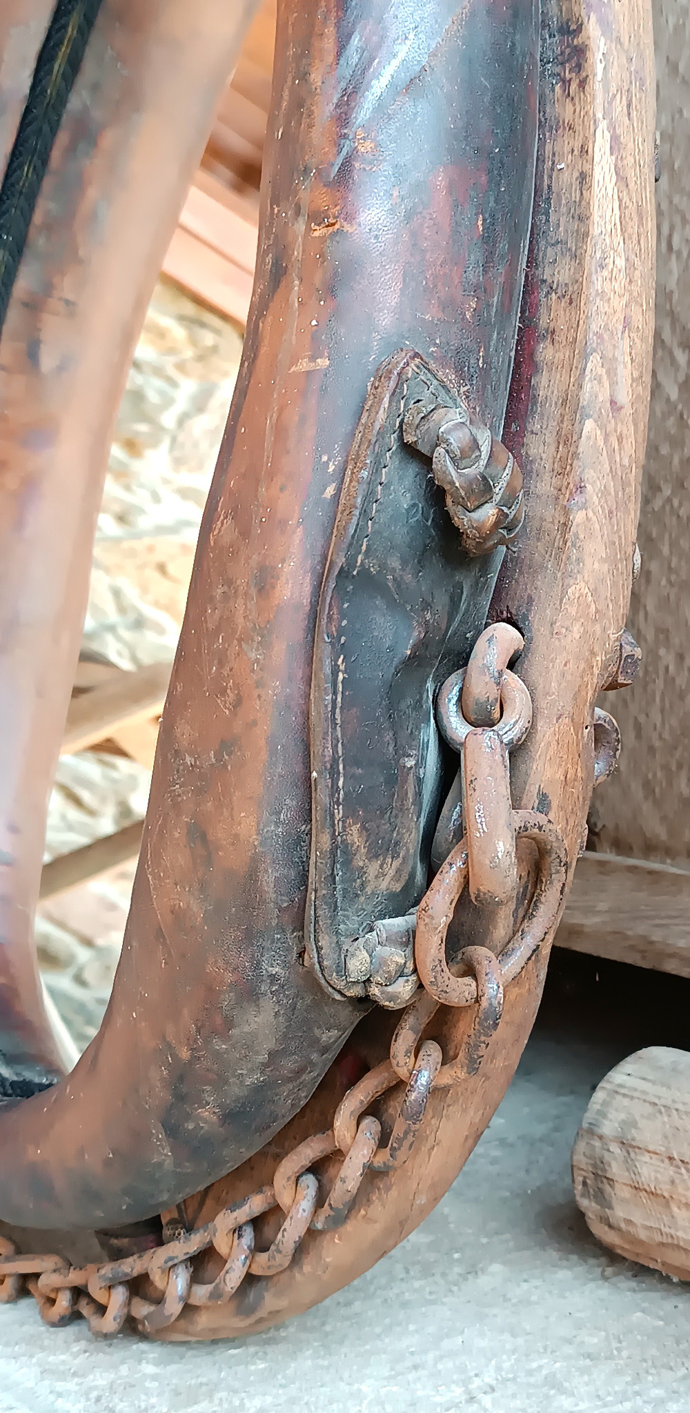 Close-up of an antique horse collar mirror showing original chain, metal rings, stitched leather fitting and aged patina