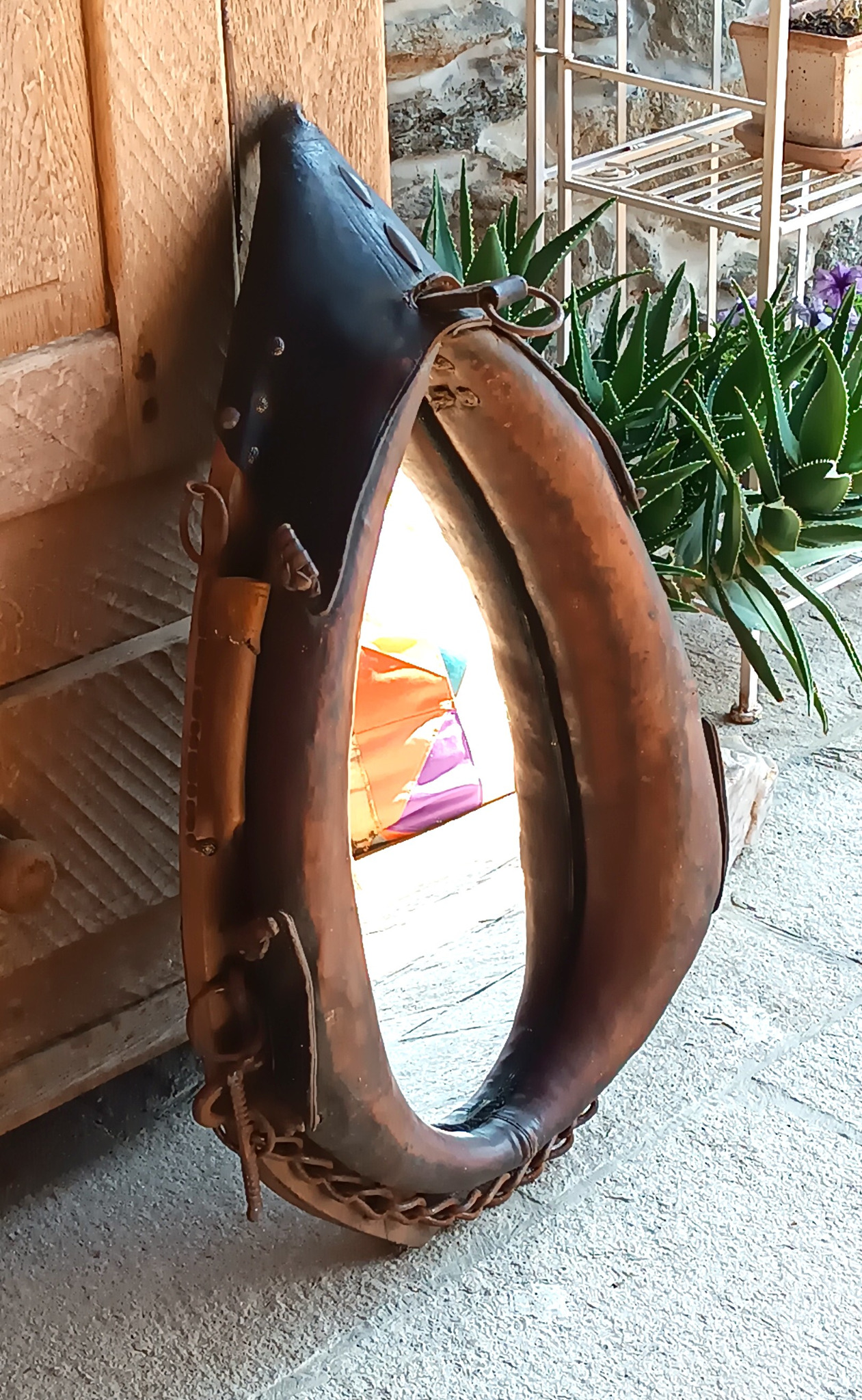 Antique horse collar mirror with original leather, metal rings, chain and aged patina, front view
