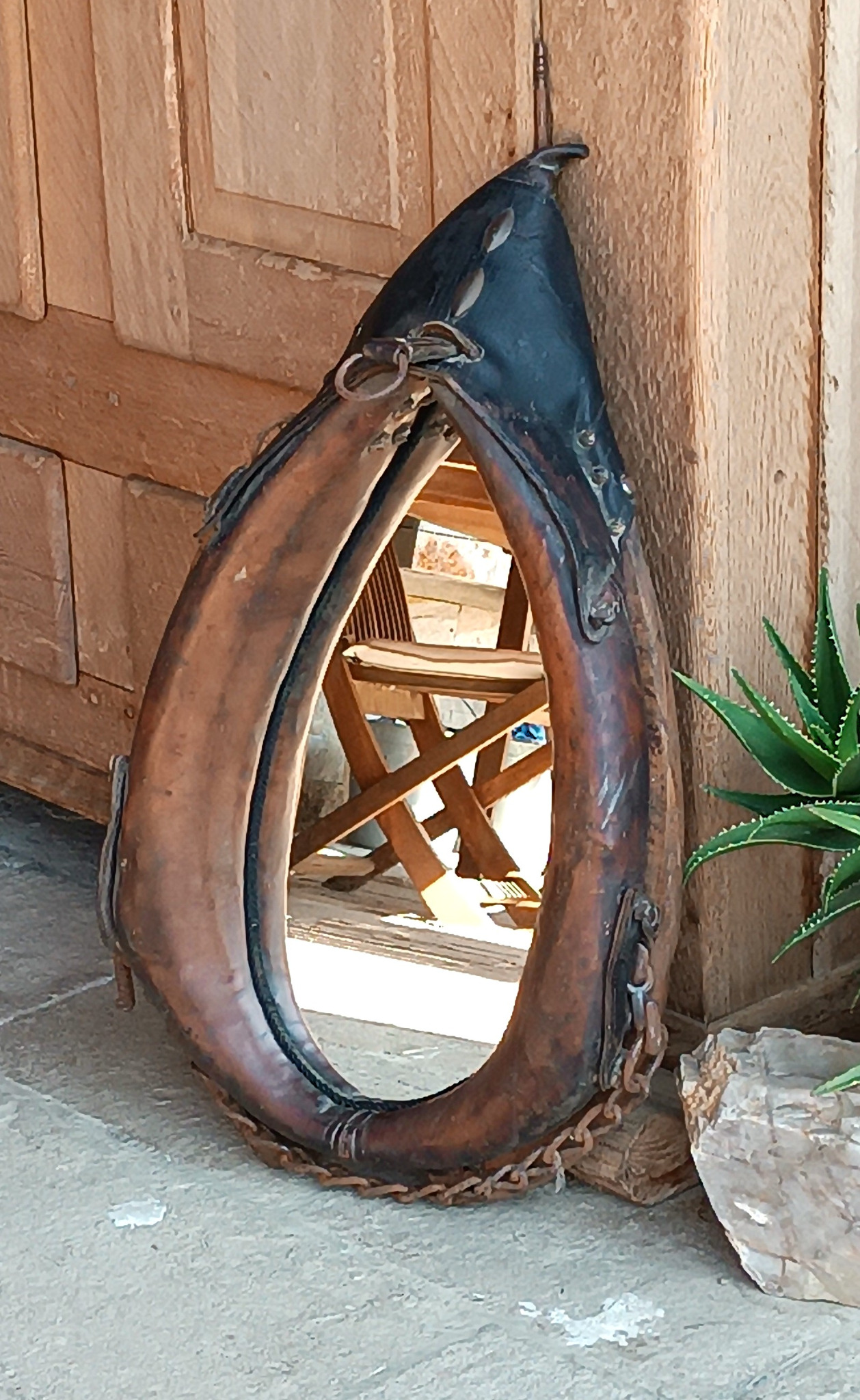 Full front view of an antique horse collar mirror with original leather, metal fittings, chain and naturally aged patina