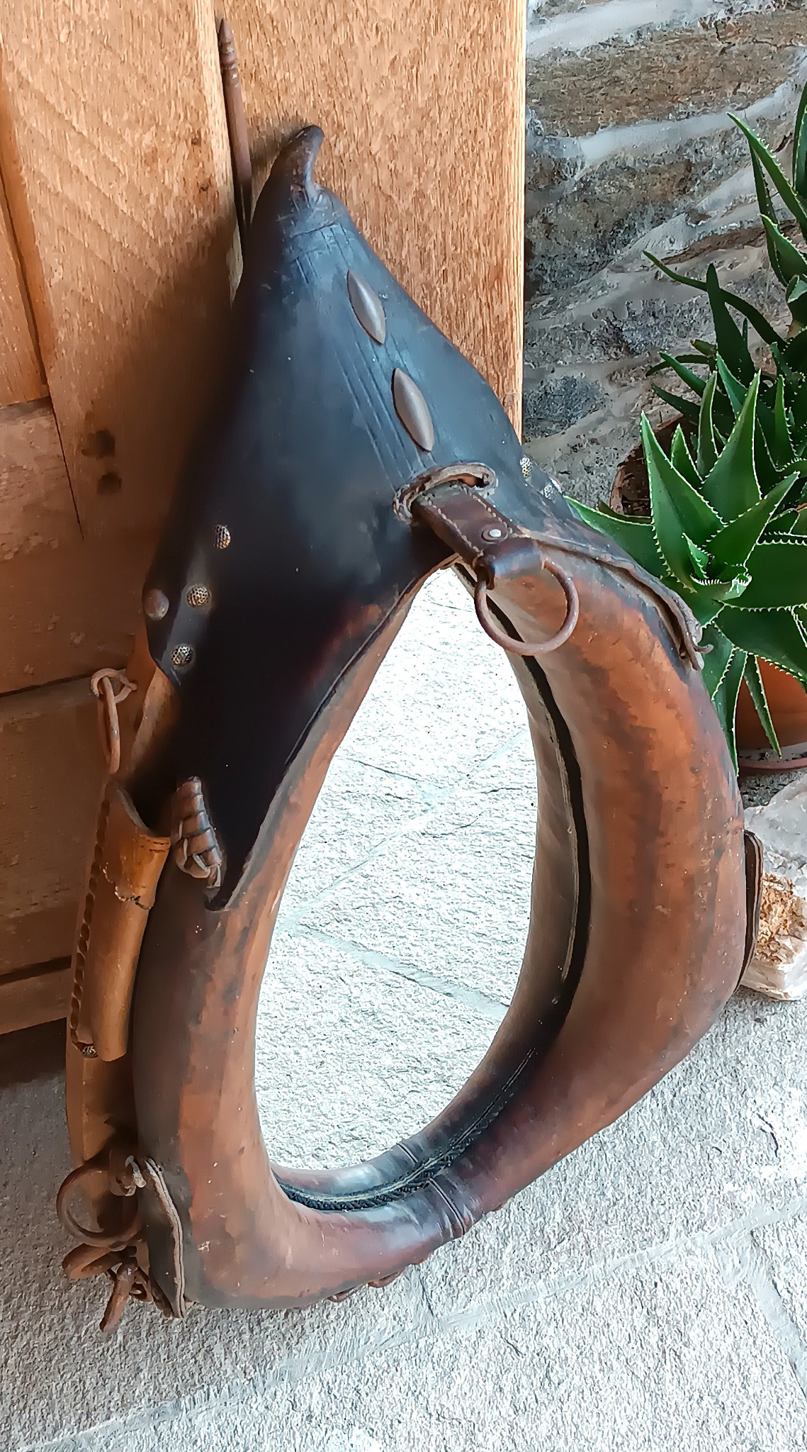 Antique horse collar mirror with original leather padding, metal rings, decorative studs and aged patina