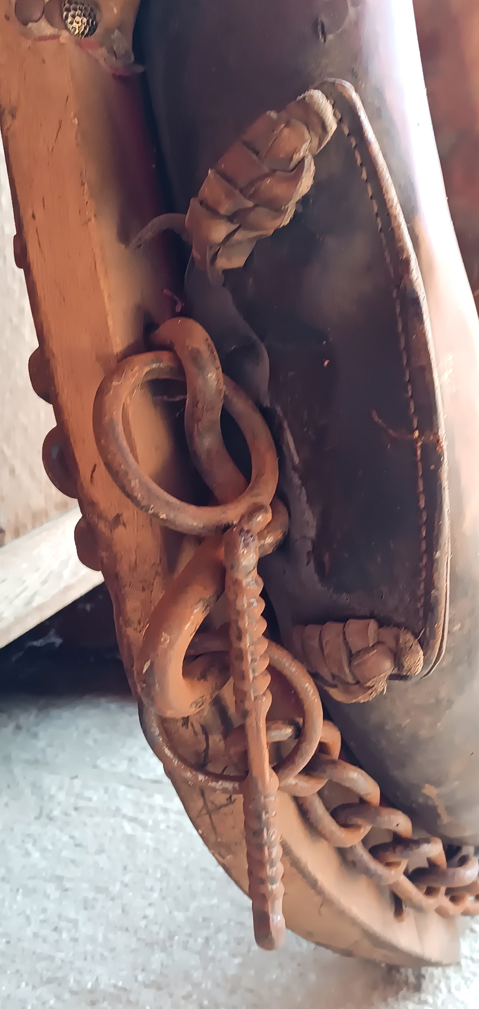 Close-up of an antique horse collar mirror showing original metal rings, chain, leather bindings and aged equestrian hardware