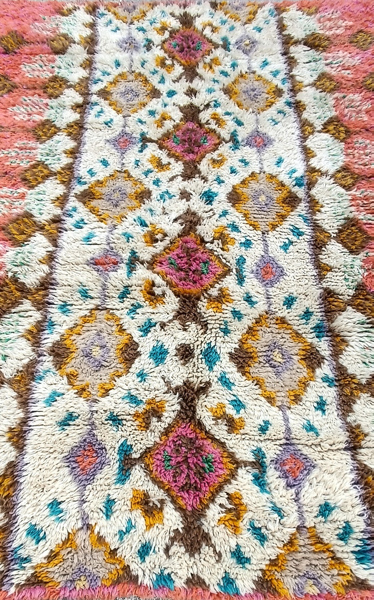 Detailed view of a vintage Bulgarian handwoven wool kitenik with cream high pile, pink diamond motifs and turquoise, mustard and brown decoration