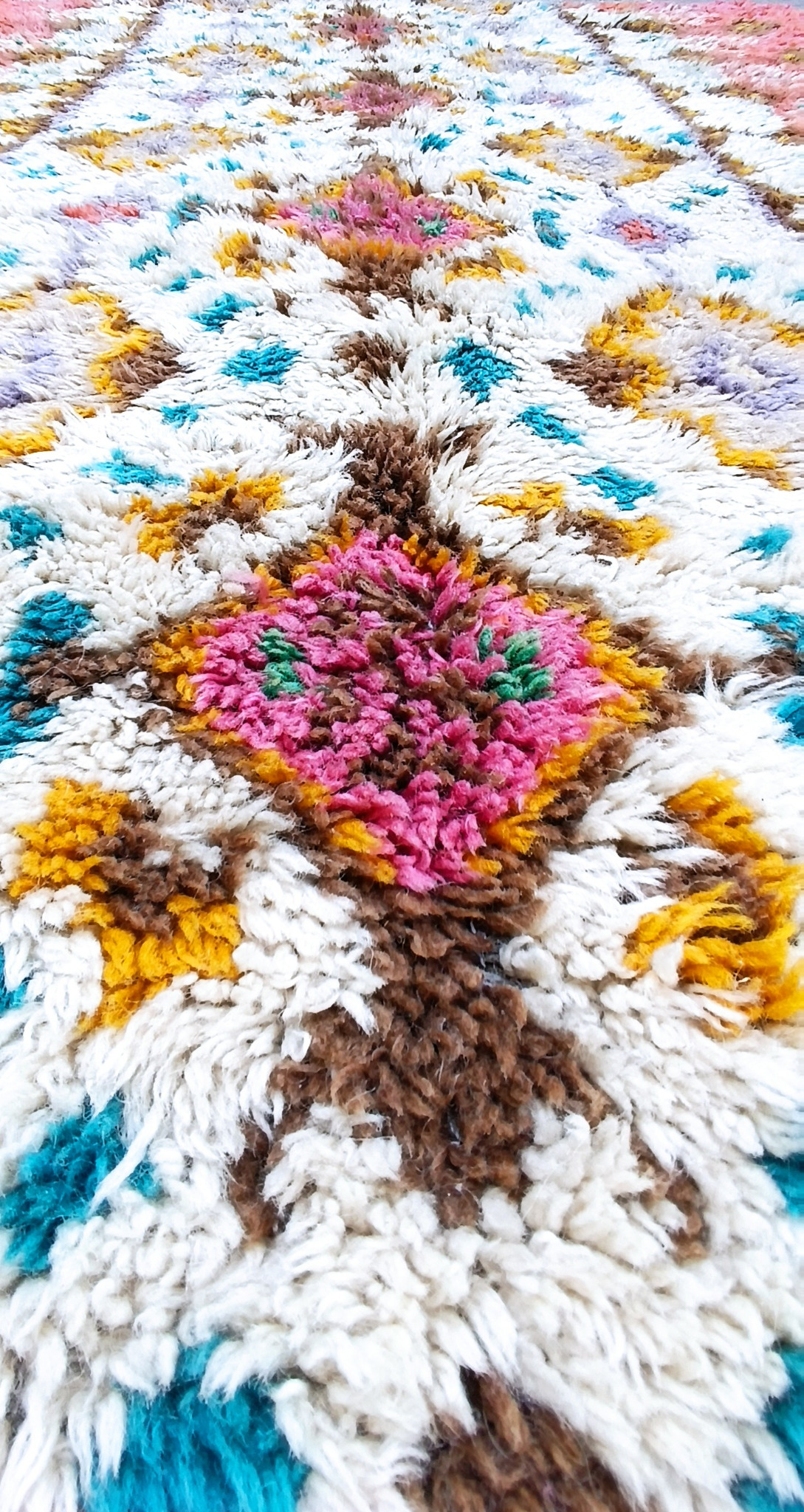 Close-up of a vintage Bulgarian wool kitenik with a pink diamond motif, cream high pile and multicoloured traditional decoration