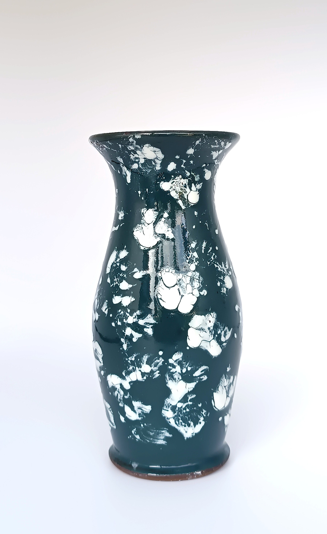 Full product image of a vintage ceramic vase with a deep dark green glossy glaze and contrasting white abstract decoration. The vase has an elongated body, gently narrowed neck, flared rim and rounded foot, measuring approximately 16 cm (6.3 in) high and 7 cm (2.8 in) wide. It is preserved in excellent vintage condition.