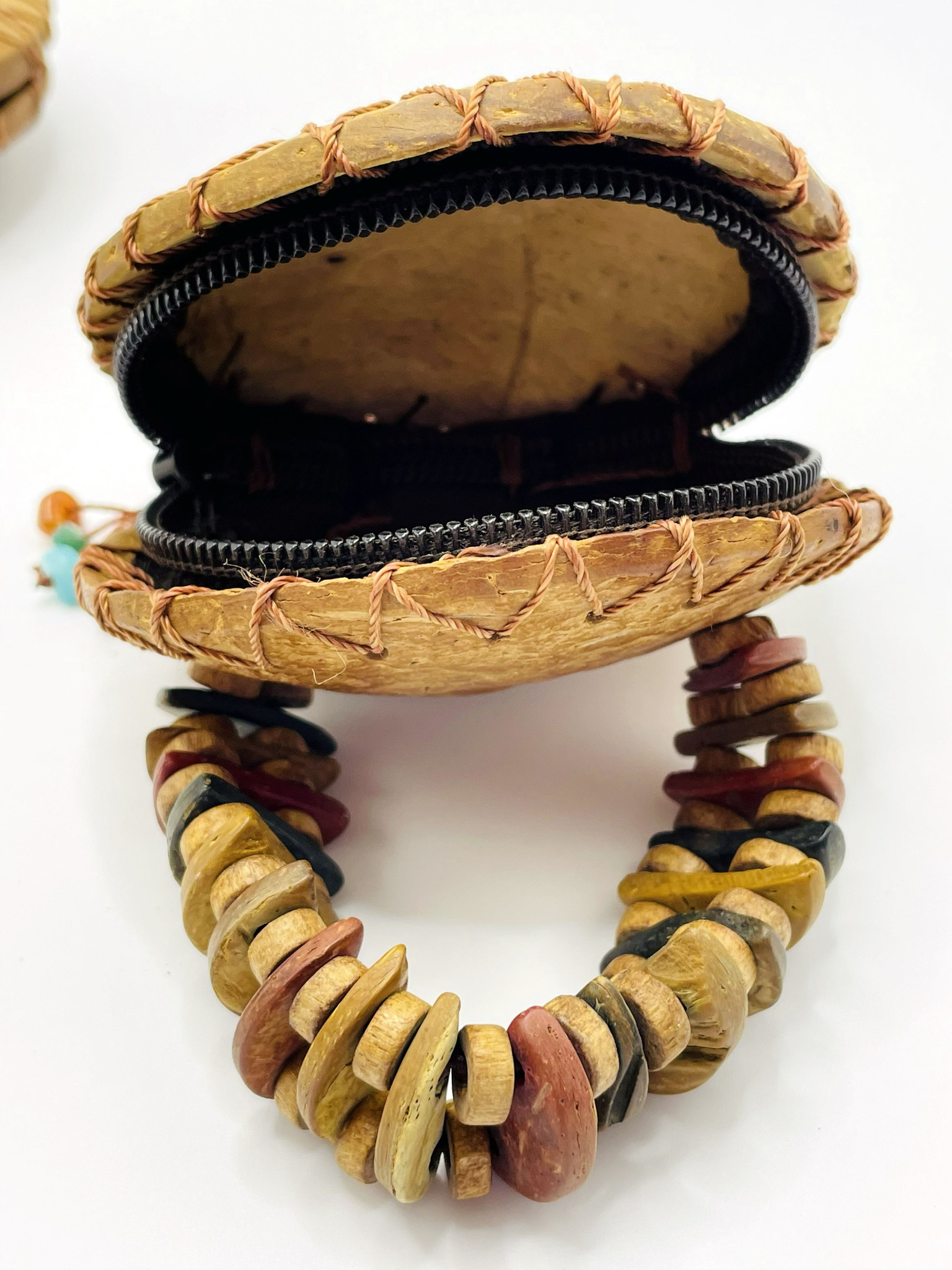 Close-up of an open vintage coconut shell purse showing the interior, zip closure, hand-stitched edges and decorative handle