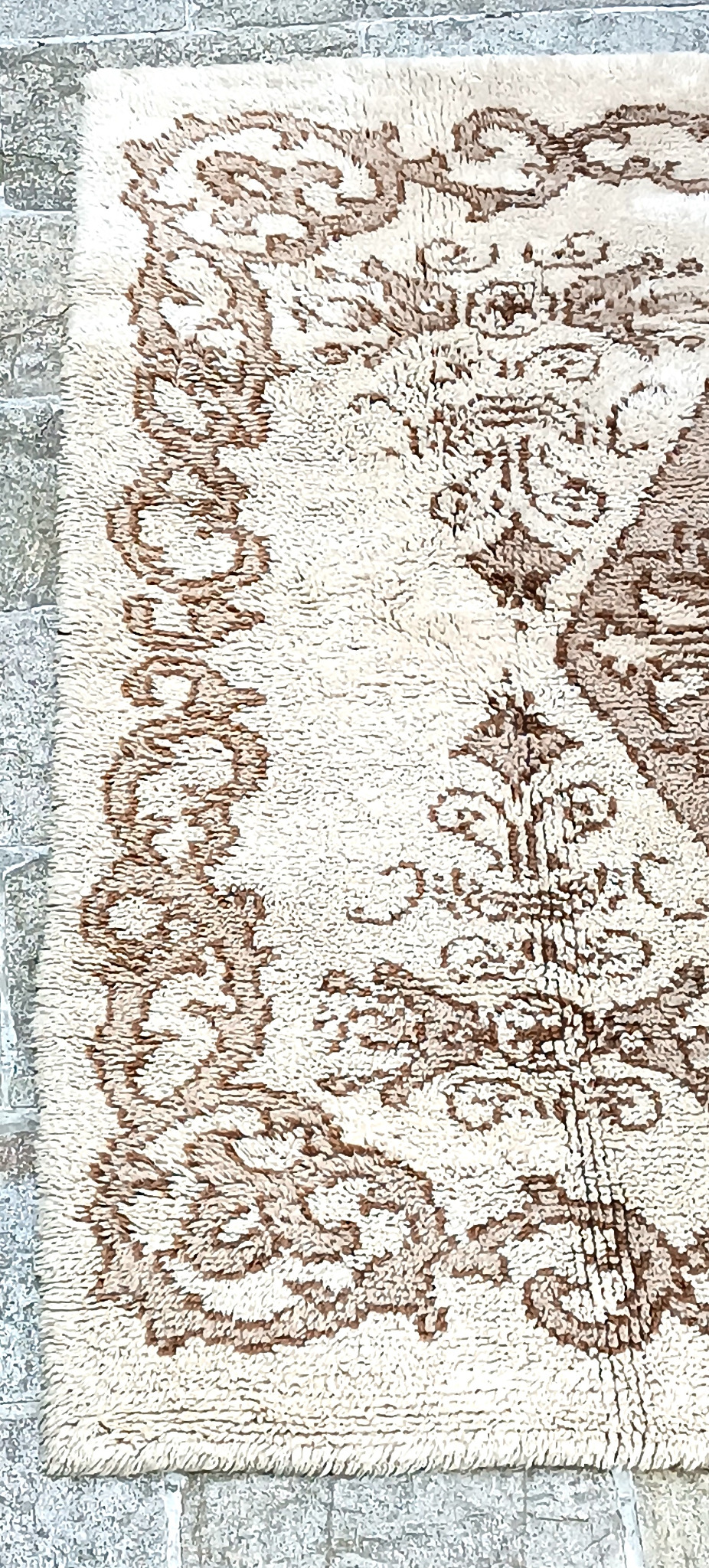 Detail of a vintage Eastern European high-pile rug with cream background, brown floral border and Oriental-inspired decoration