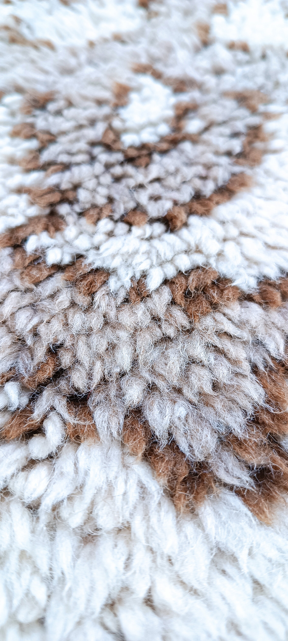 Macro close-up of a vintage Eastern European high-pile rug showing dense cream, beige and brown fibres and textured pile