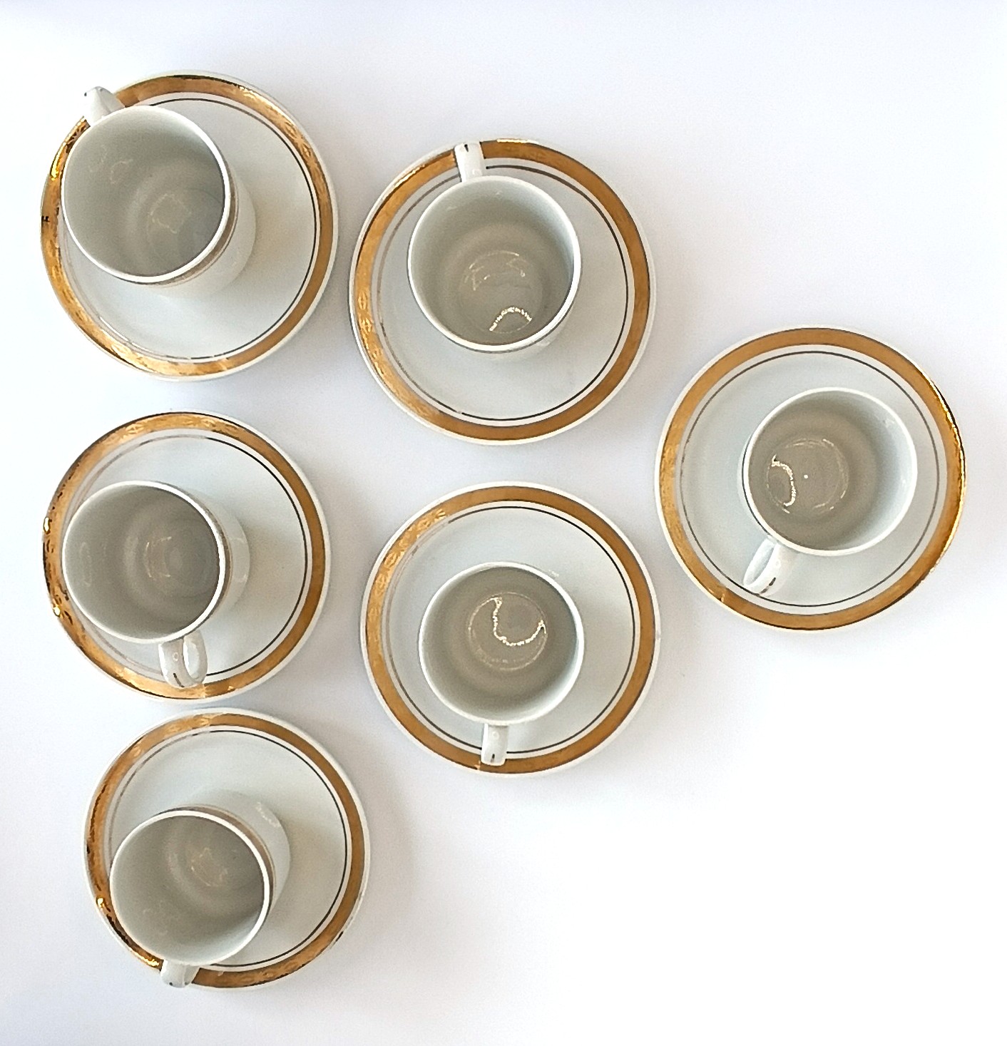 Top view of six vintage Bulgarian Kitka porcelain coffee cups and saucers with gold-tone bands and fine border decoration