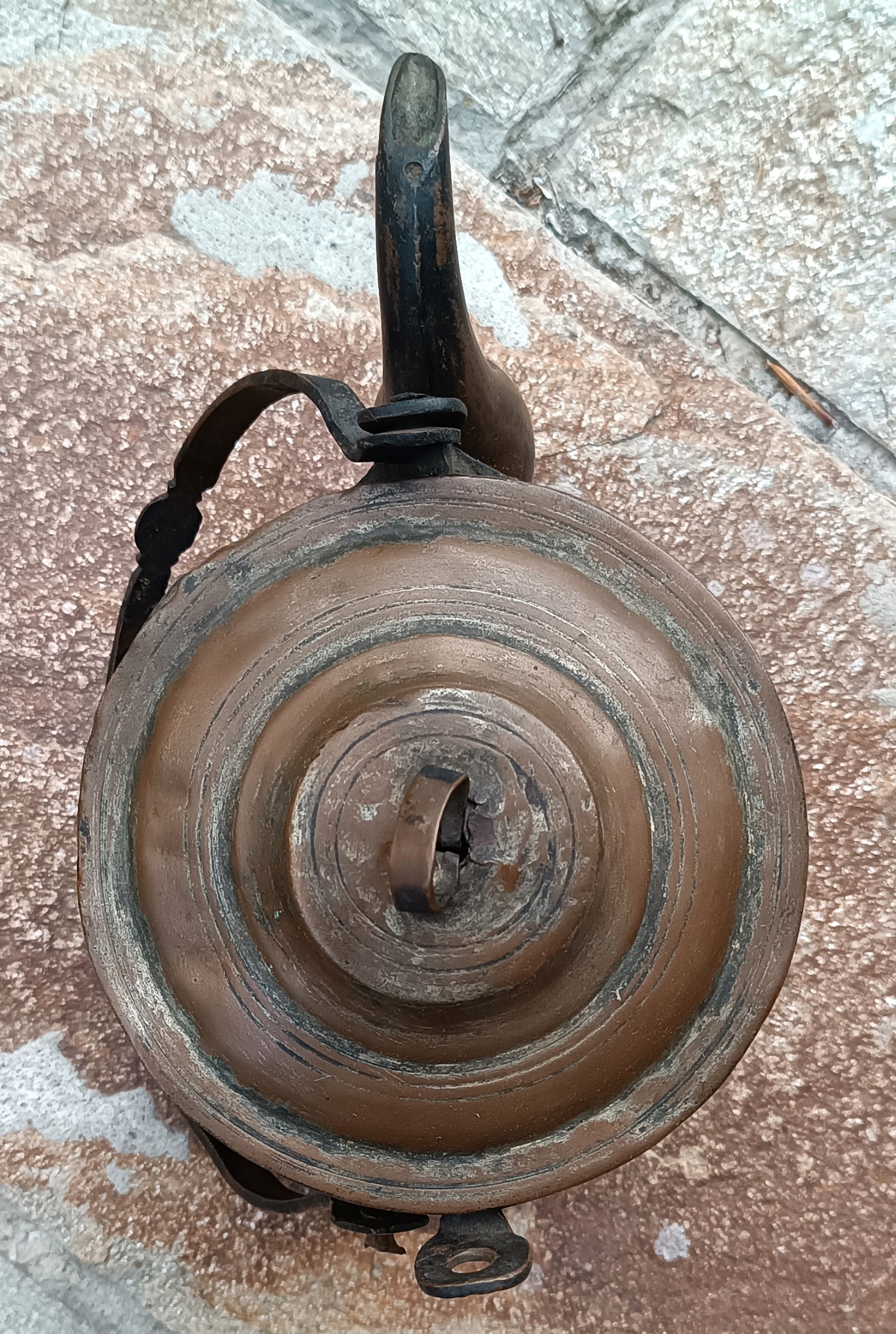 Top view of antique copper kettle lid showing raised concentric rings, domed central knob and traditional metalworking details