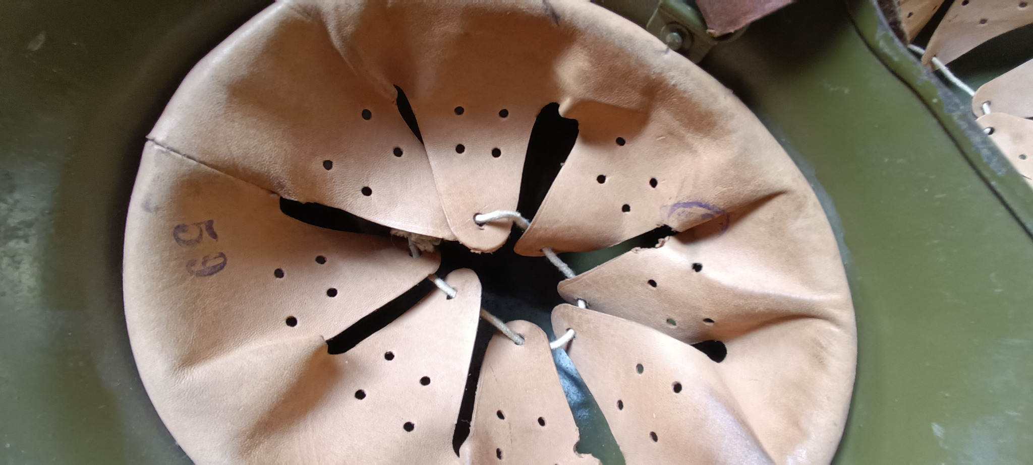 Close-up of Bulgarian M36 Type A helmet interior showing leather liner size marking 59, possible inspection stamp and rolled steel rim
