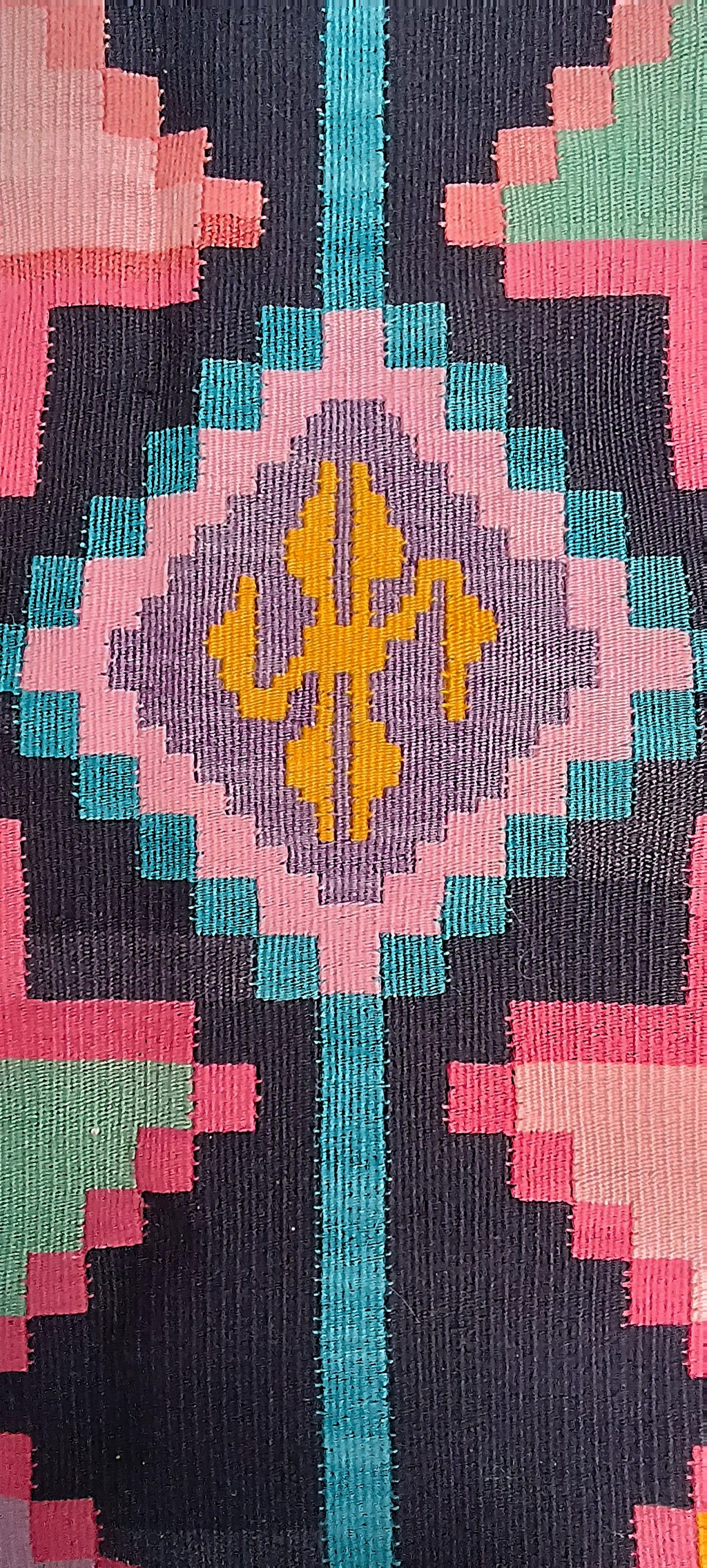 Golden geometric motif within a lavender diamond medallion, bordered by pink and turquoise stepped patterns on a Bulgarian Chiprovtsi rug.