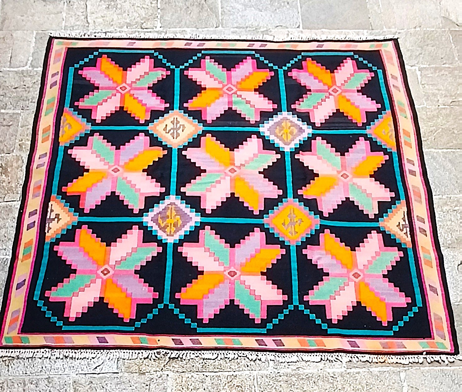 Full view of a traditional Chiprovtsi Christmas Star rug with nine colourful geometric stars on a black background.