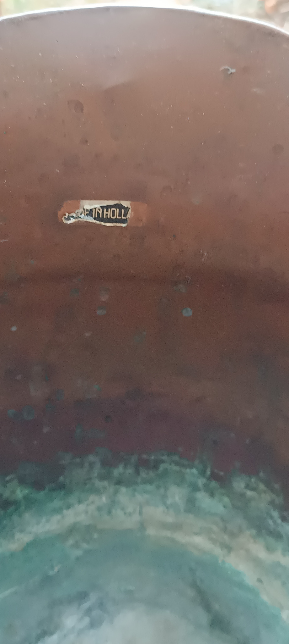 Partially preserved Made in Holland paper label inside a vintage Dutch copper coal scuttle, evidence of the marked vessel's stated country of origin