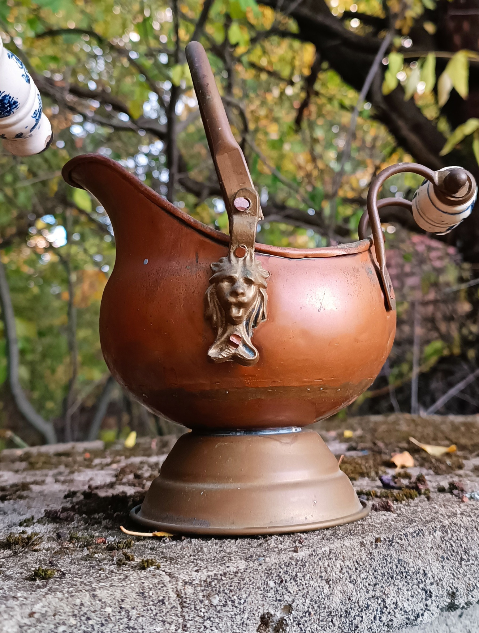 Small vintage Dutch copper coal scuttle with helmet-shaped pouring lip, decorative lion-head mount and blue-and-white Delft-style ceramic handle