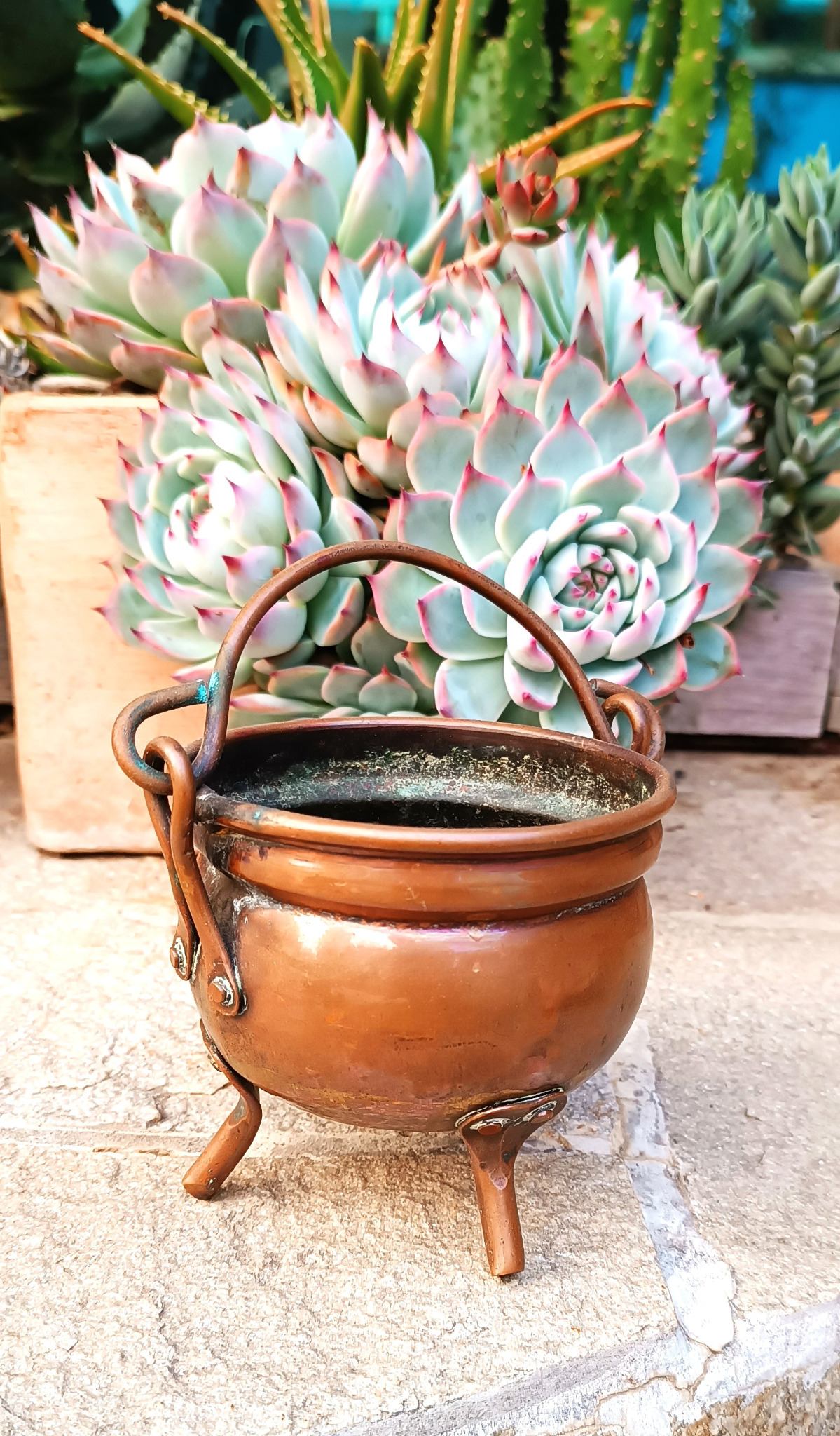Small vintage three-legged copper-coloured cauldron with rounded open body, rolled rim and movable swing handle