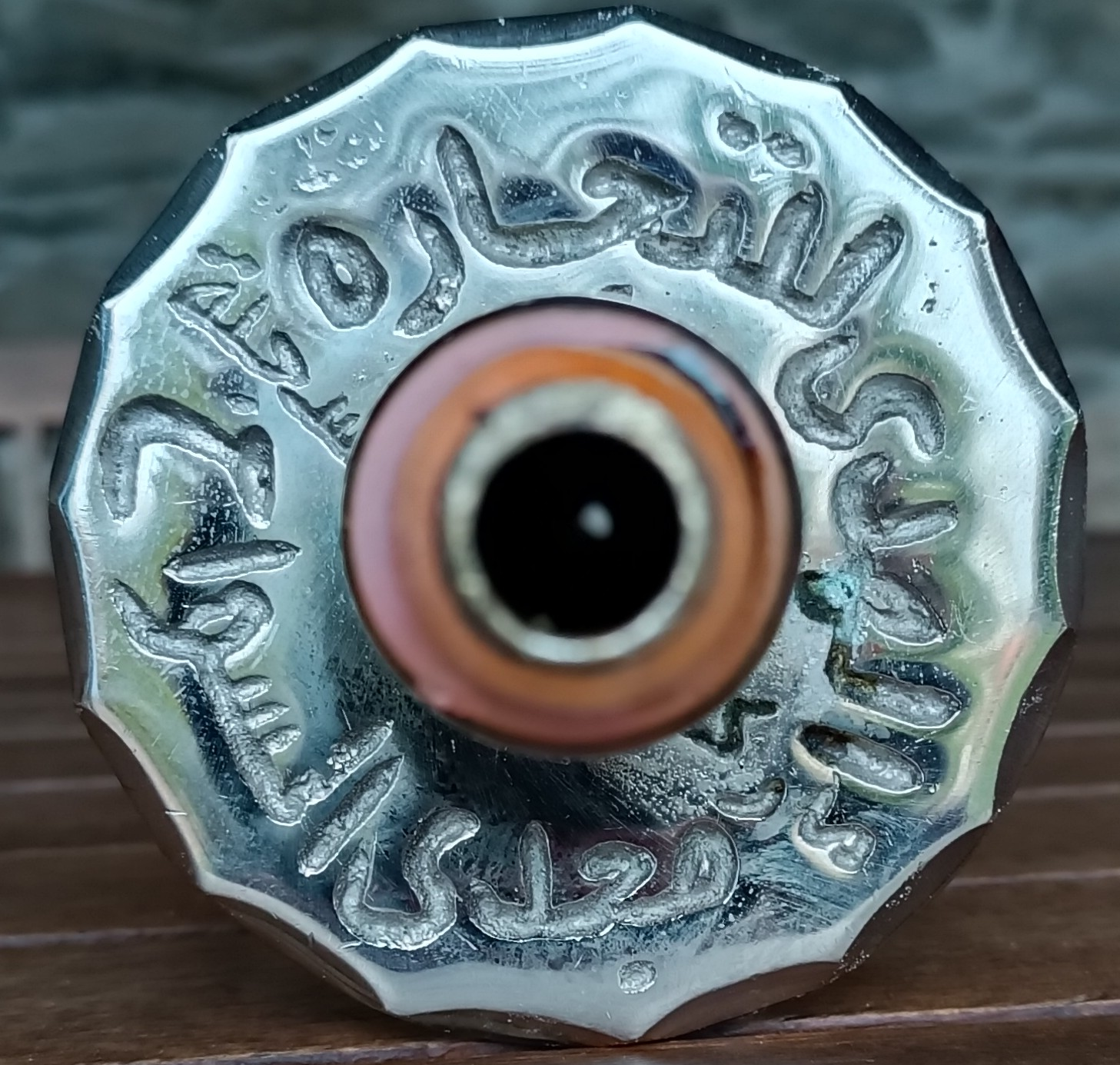 Macro photograph of raised Arabic lettering on a scalloped polished metal fitting of a vintage Egyptian hookah attributed to Yehia El Khawanky