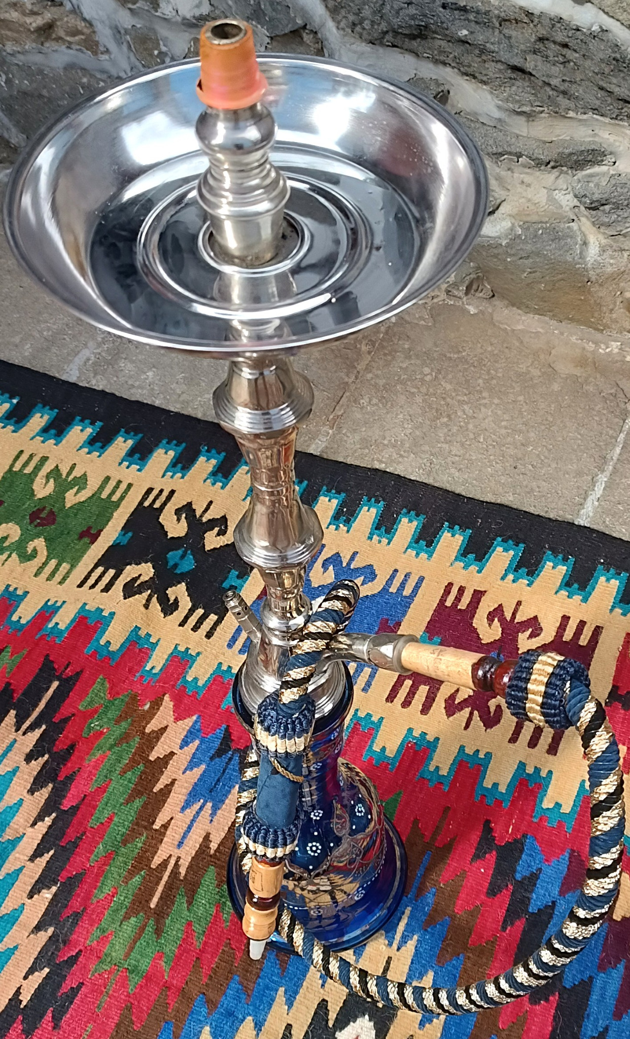 Overhead view of a vintage Egyptian Yehia El Khawanky hookah showing the polished circular metal tray, central stem, cobalt-blue glass base and braided hose