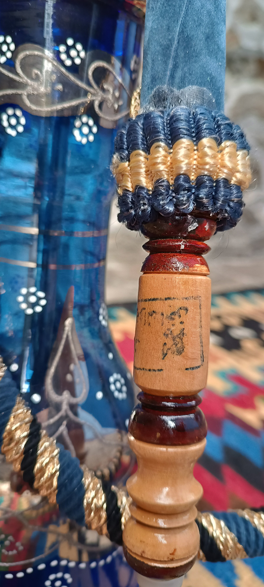 Close-up of the original wooden mouthpiece of a vintage Yehia El Khawanky Egyptian hookah, showing blue-and-gold braided trim, faded markings and turned wood.
