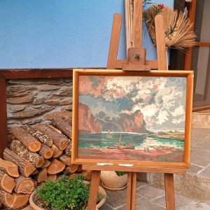 Vintage Wiehler Gobelin Storm over Lake Mondsee, hand-embroidered in 1980s Bulgaria, displayed in a wooden frame on an easel in a rustic courtyard.